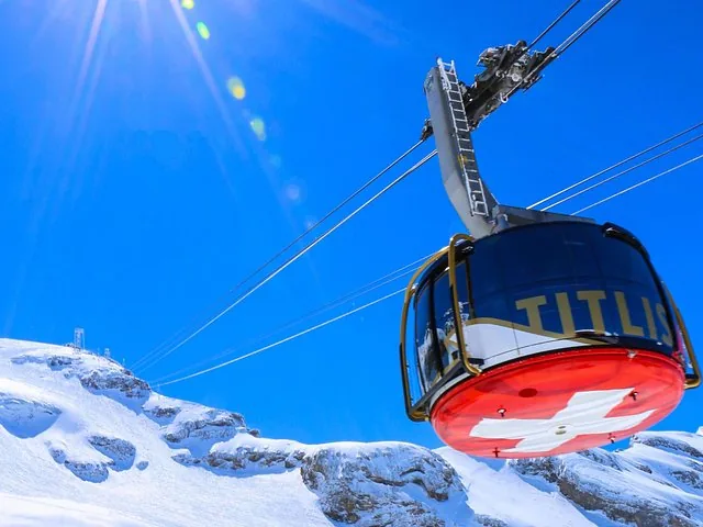 A cable car ascending over a snowy alpine landscape with mountains beyond