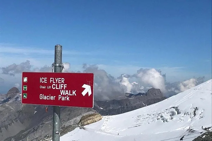 A Titlis cable car with a Swiss flag design hanging above snowy mountains