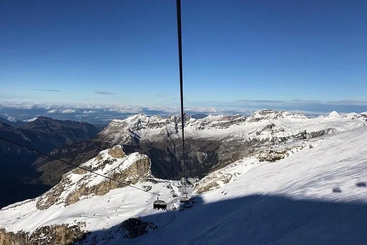 A cable car moving up the mountain under a bright sunny sky
