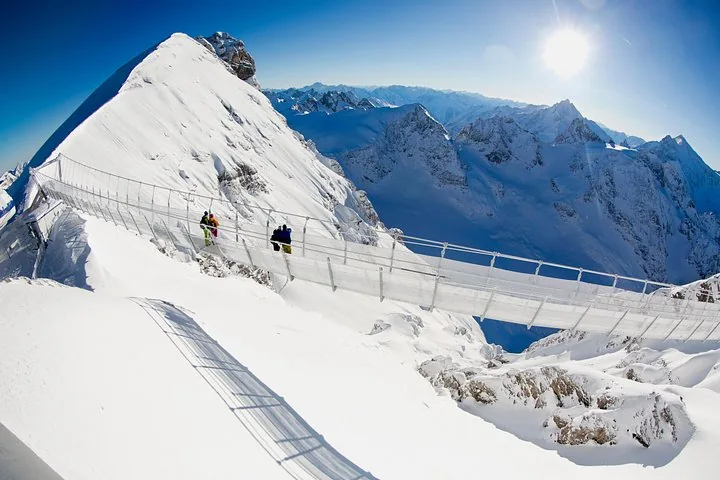People walking across the Titlis Cliff Walk suspension bridge in the snow