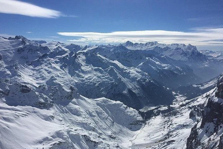Aerial view of snow-capped mountains and valleys under a blue sky