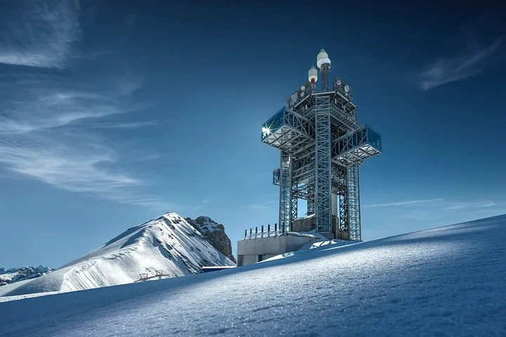 A tall communication and observation tower structure atop the snowy Mount Titlis