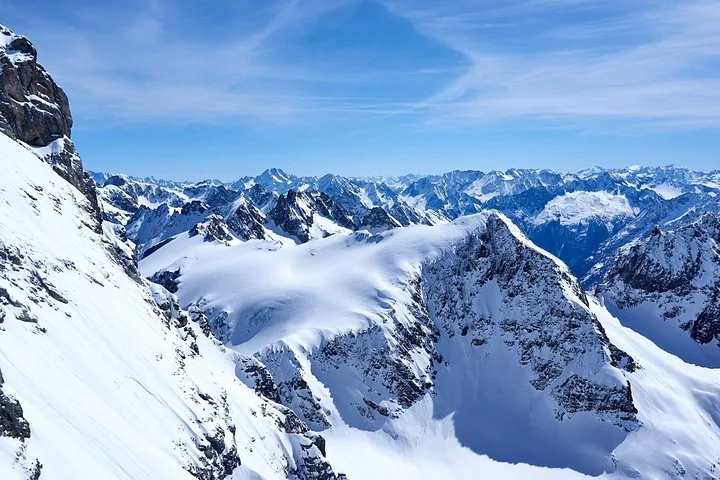 A Titlis Rotair cable car near the snowy summit against a bright sun